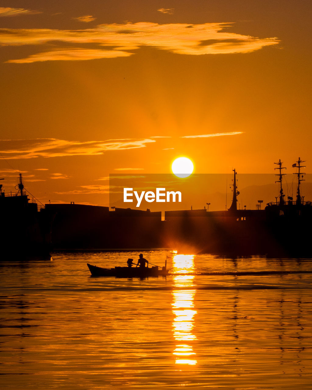 Silhouette boats in sea against orange sky