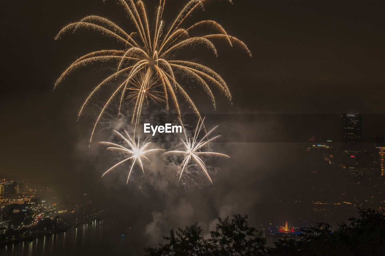 Firework display over city against sky at night