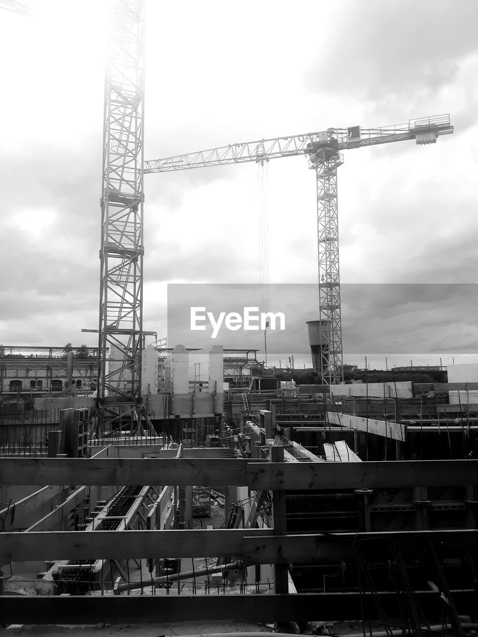 Cranes at construction site against sky in city