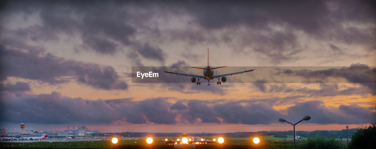 low angle view of airplane flying in sky at sunset