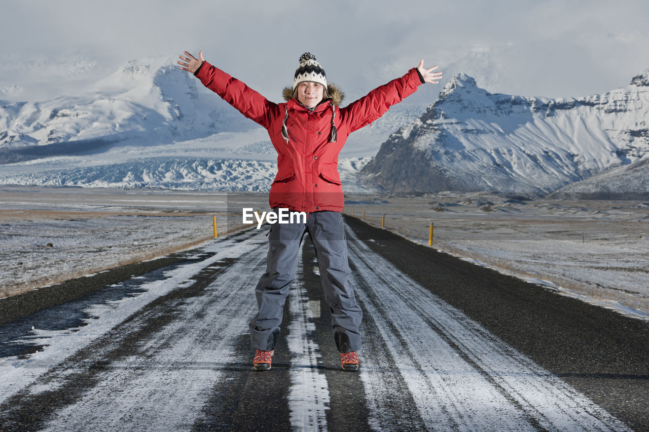 Woman standing in the middle of a highway with her arms stretched out