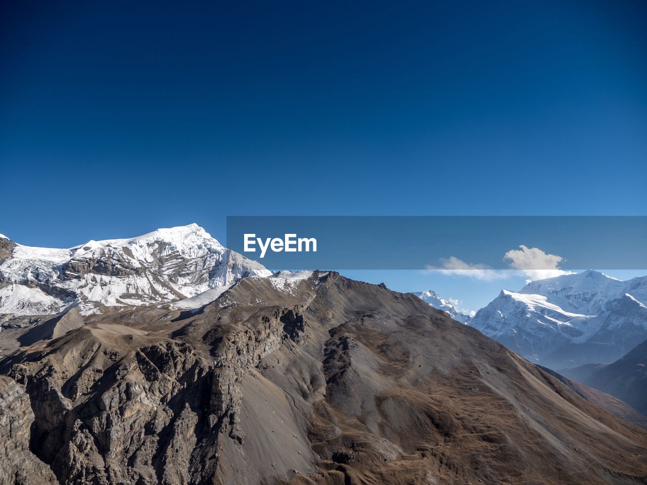 Scenic view of snowcapped mountains against clear blue sky