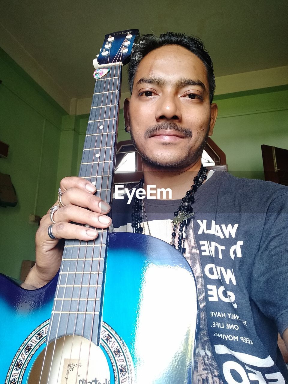 Portrait of man holding guitar siting at home