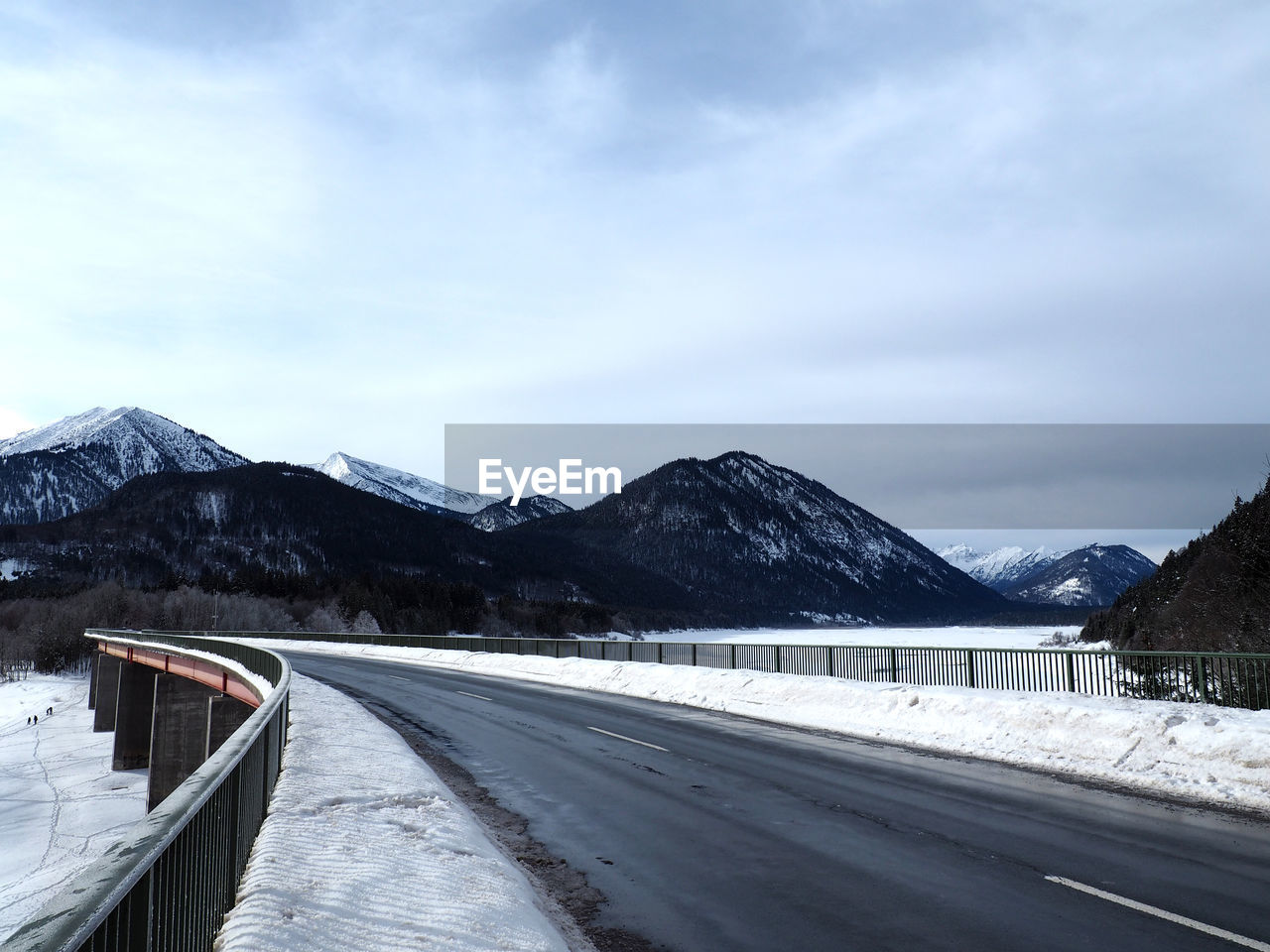 Road and mountains against cloudy sky during winter