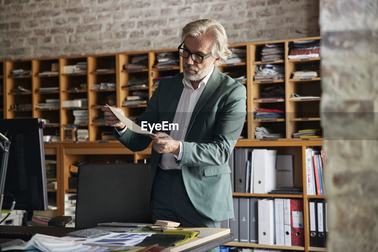 Male design professional examining fabric in office