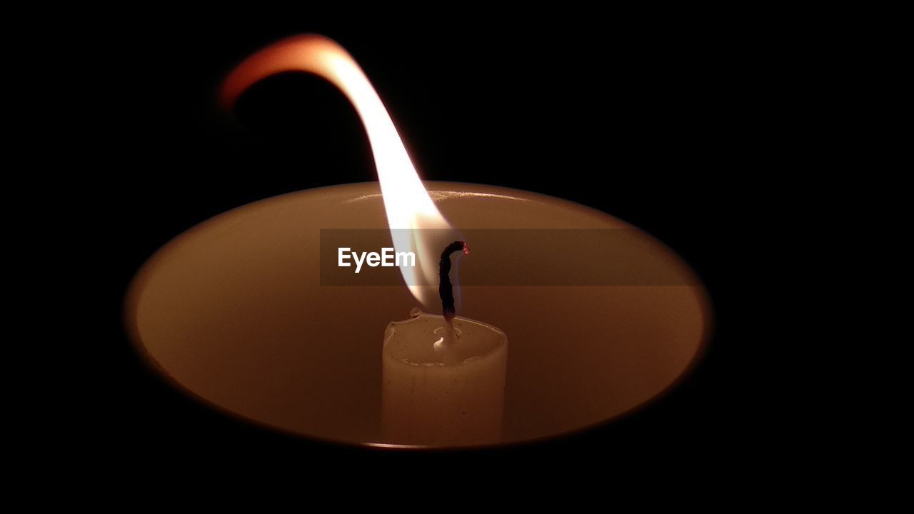 Close-up of lit candle against black background