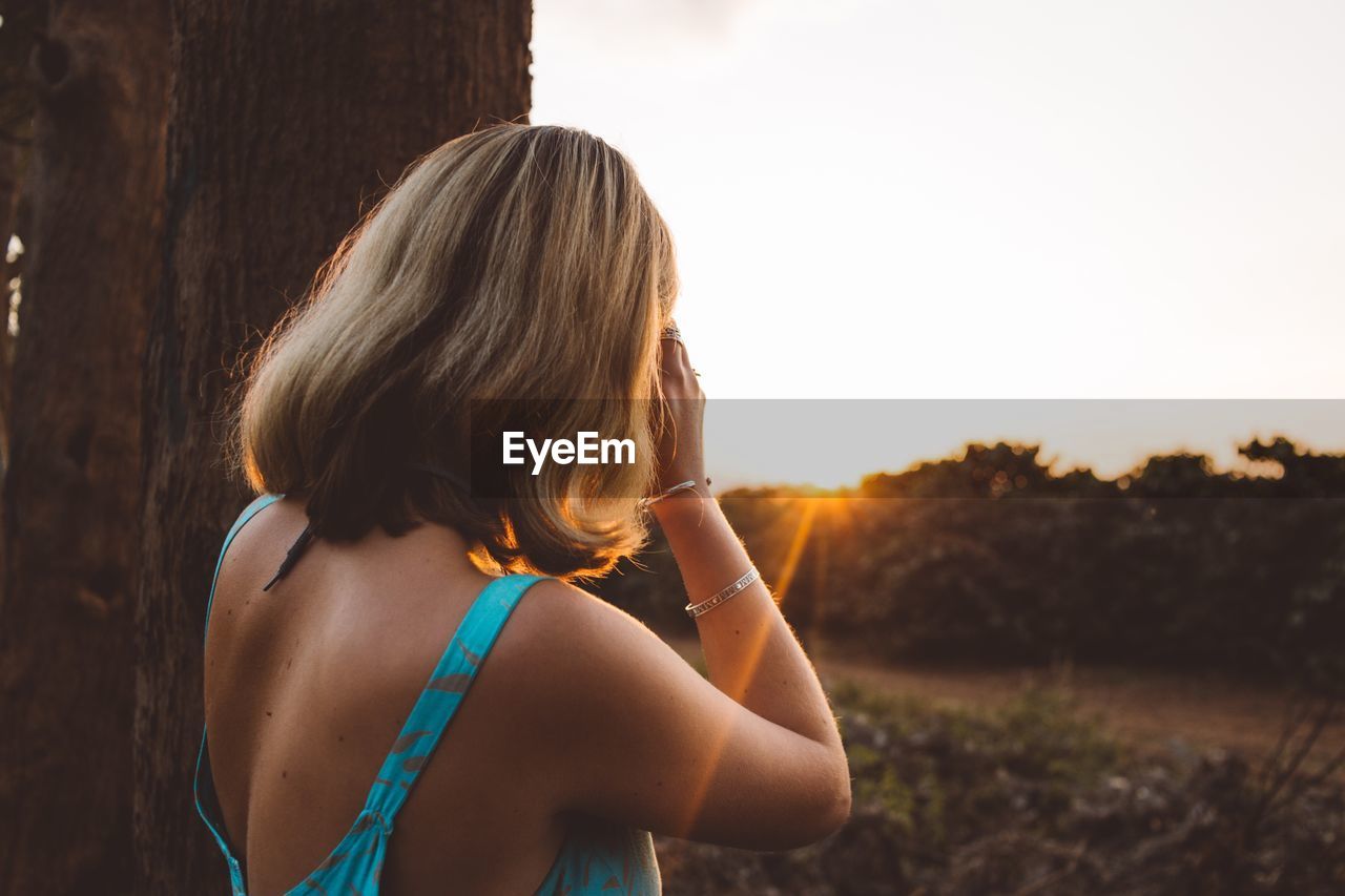 Side view of woman standing against clear sky during sunset