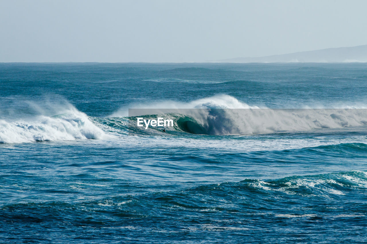 Scenic view of wave rushing sea against clear sky