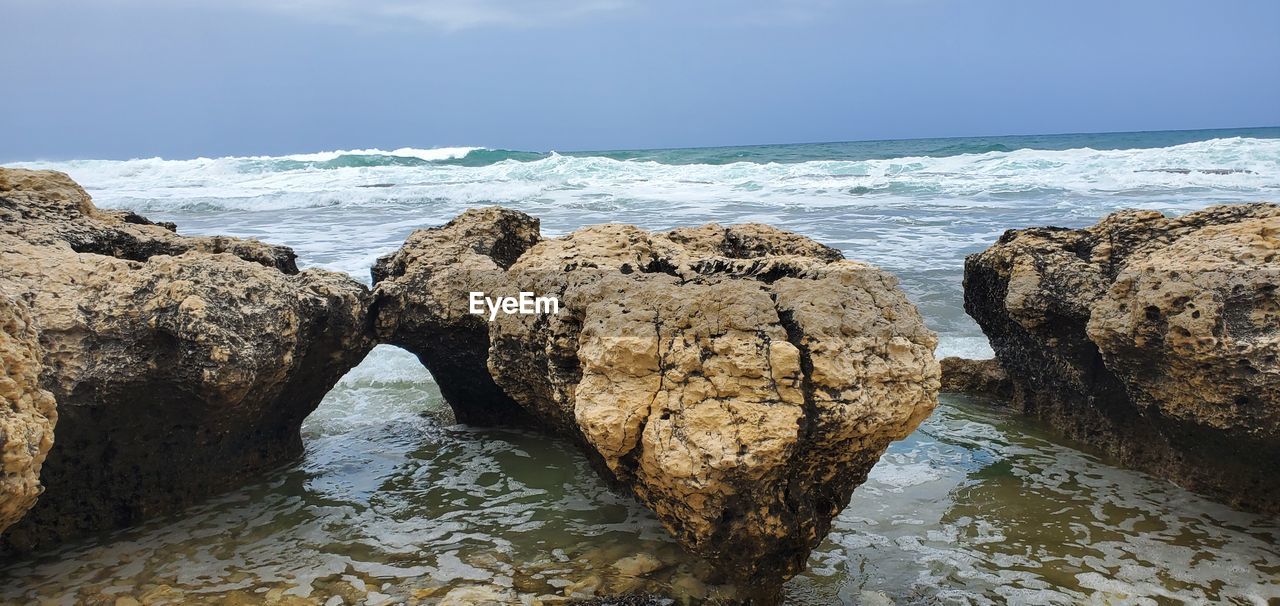 water, rock, sea, shore, coast, land, beach, ocean, sky, body of water, nature, wave, beauty in nature, scenics - nature, horizon over water, no people, cloud, tranquility, horizon, geology, day, cliff, rock formation, terrain, outdoors, motion, bay, sand, environment, tranquil scene, wind wave, travel destinations, cove, formation, coastline, travel, non-urban scene