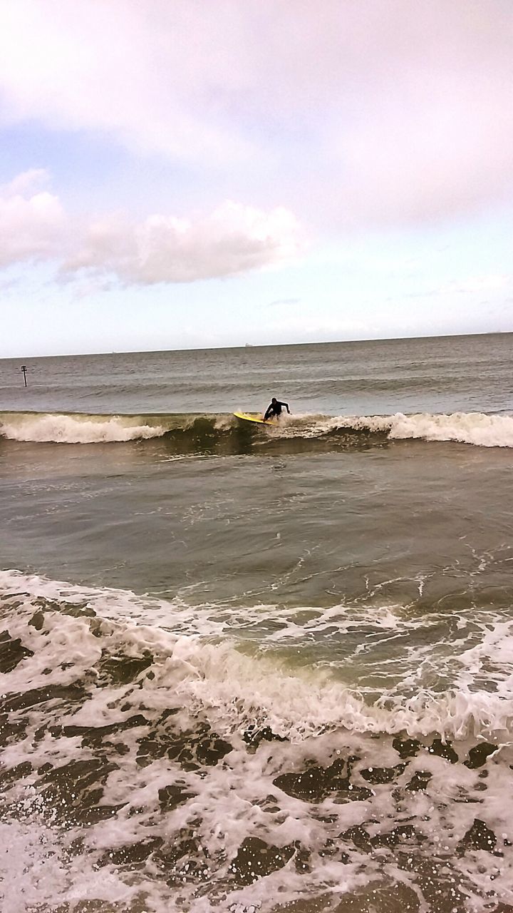 Man surfing on sea wave against sky