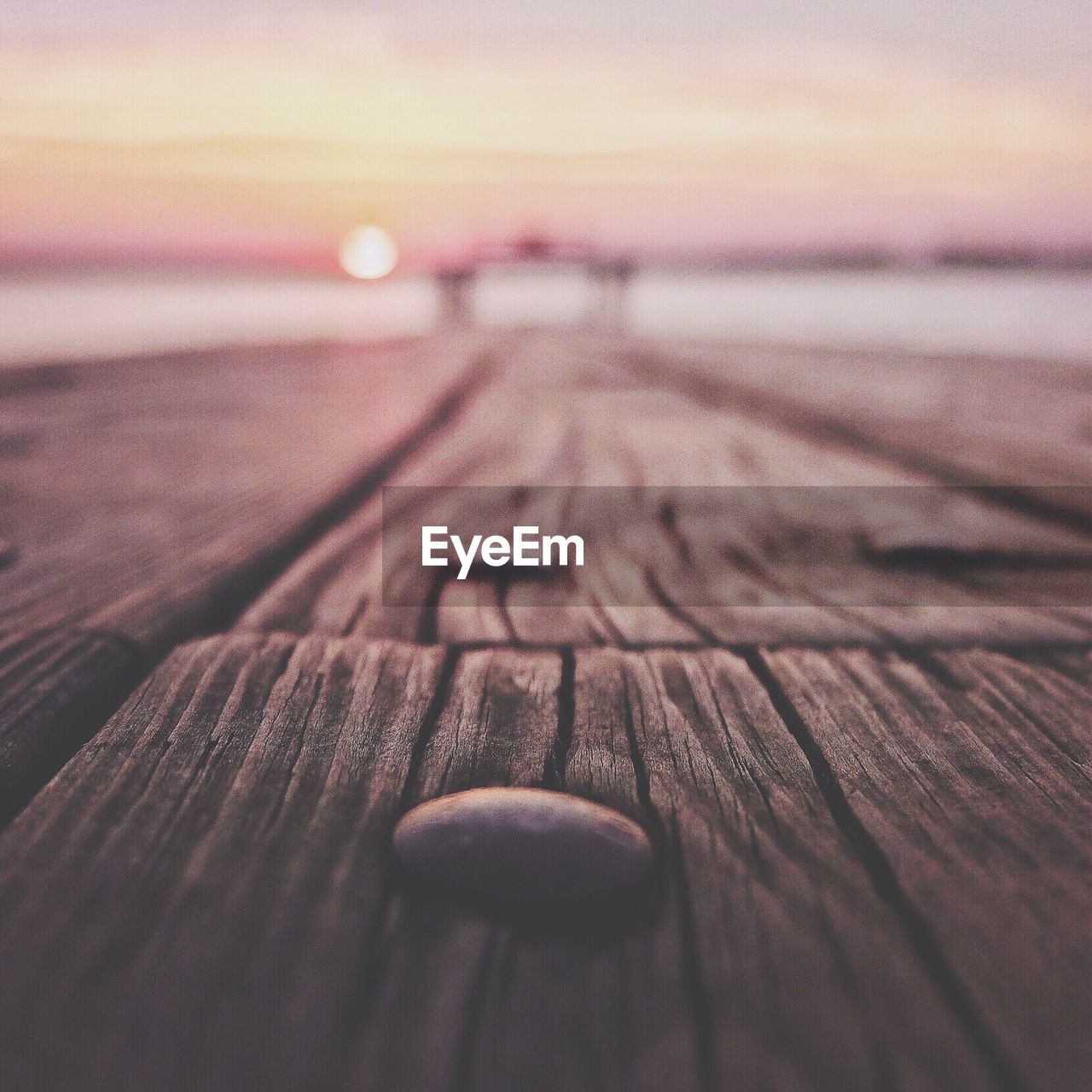 Surface level of wooden jetty at lake against sky during sunrise