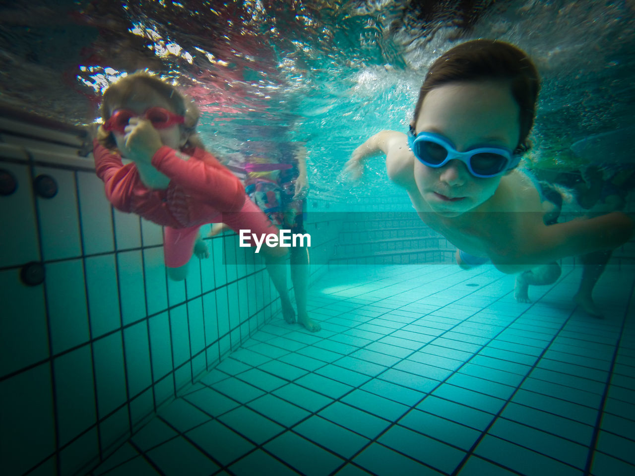 A boy and a girl swimming underwater in a pool 