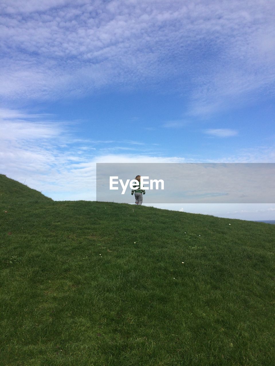 Low angle view of girl standing on grassy field against sky