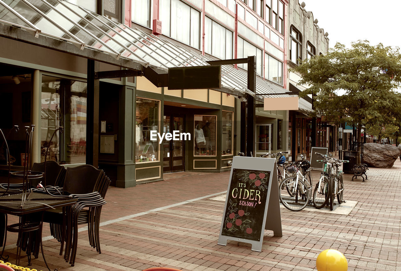 CHAIRS AND TABLES ON STREET BY BUILDINGS