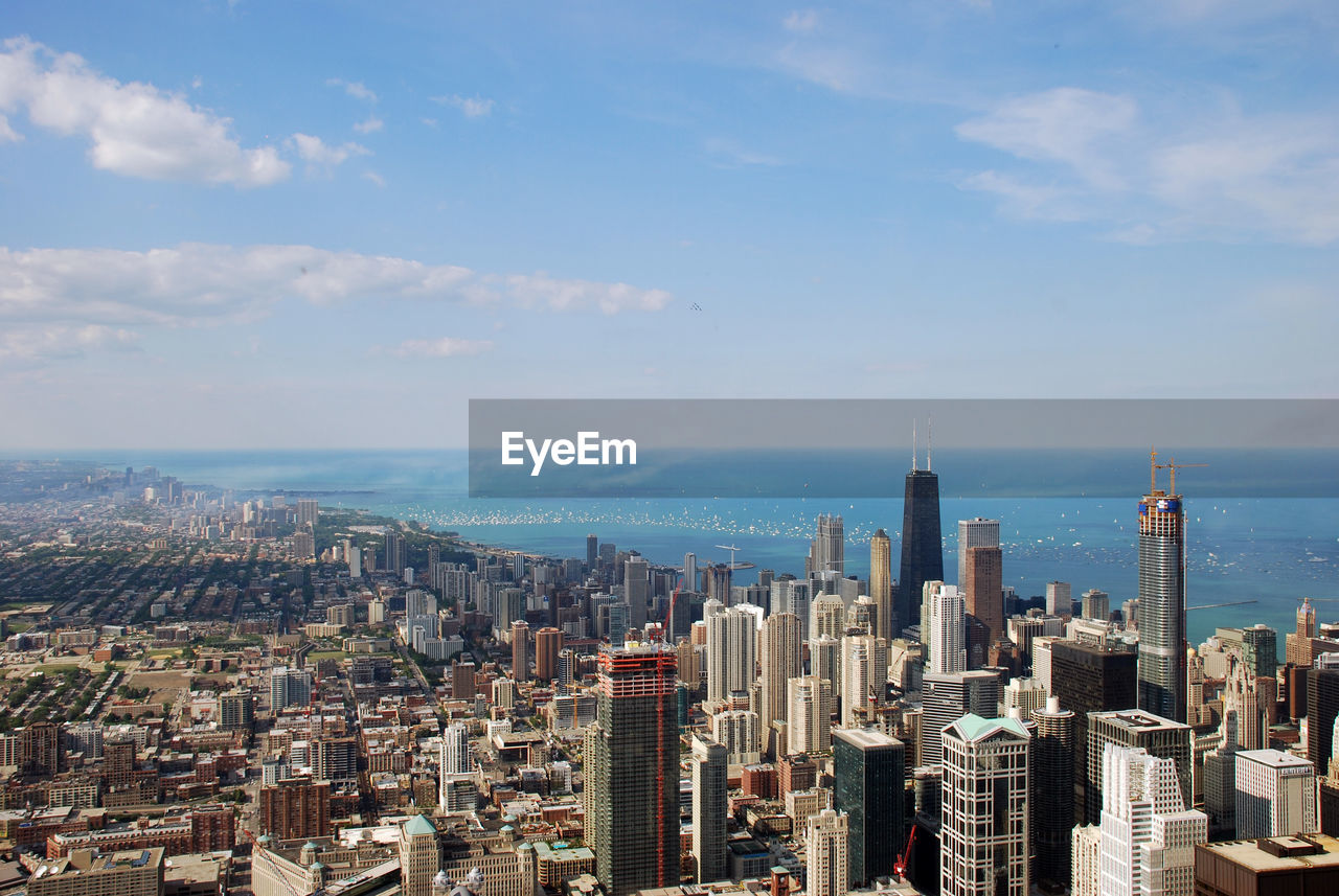 Aerial view of buildings in city against cloudy sky