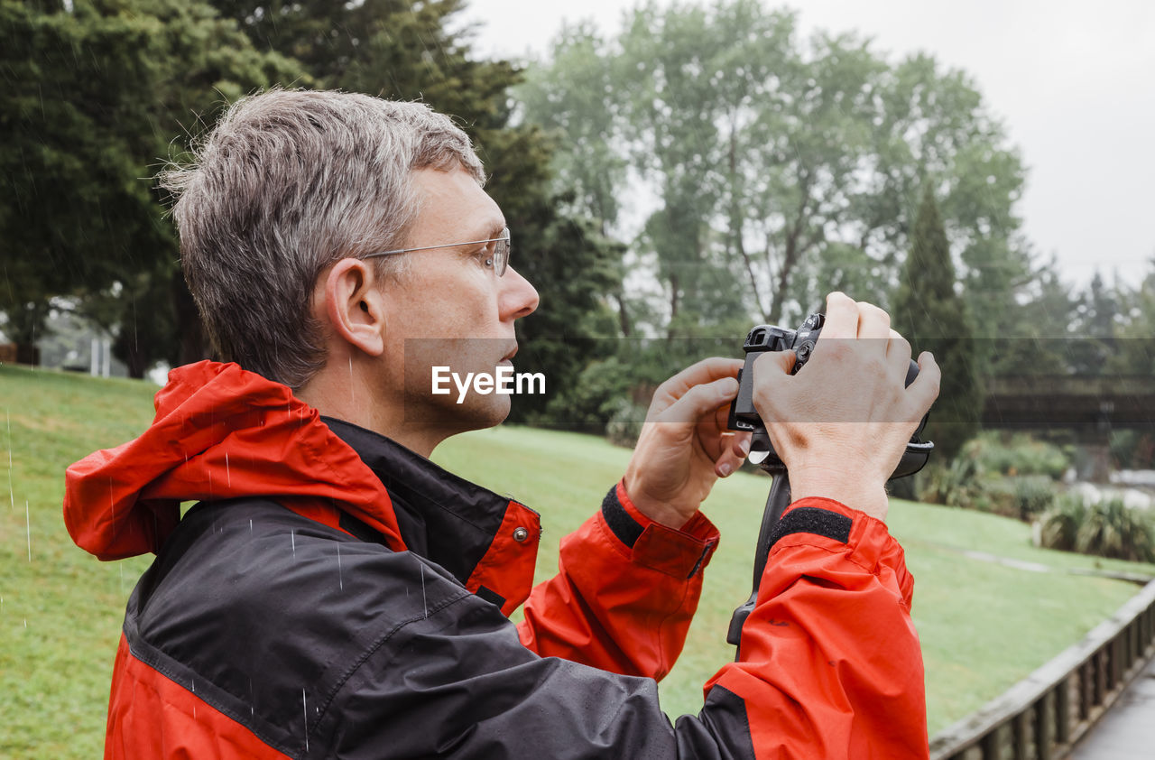 Mature man photographing with camera outdoors