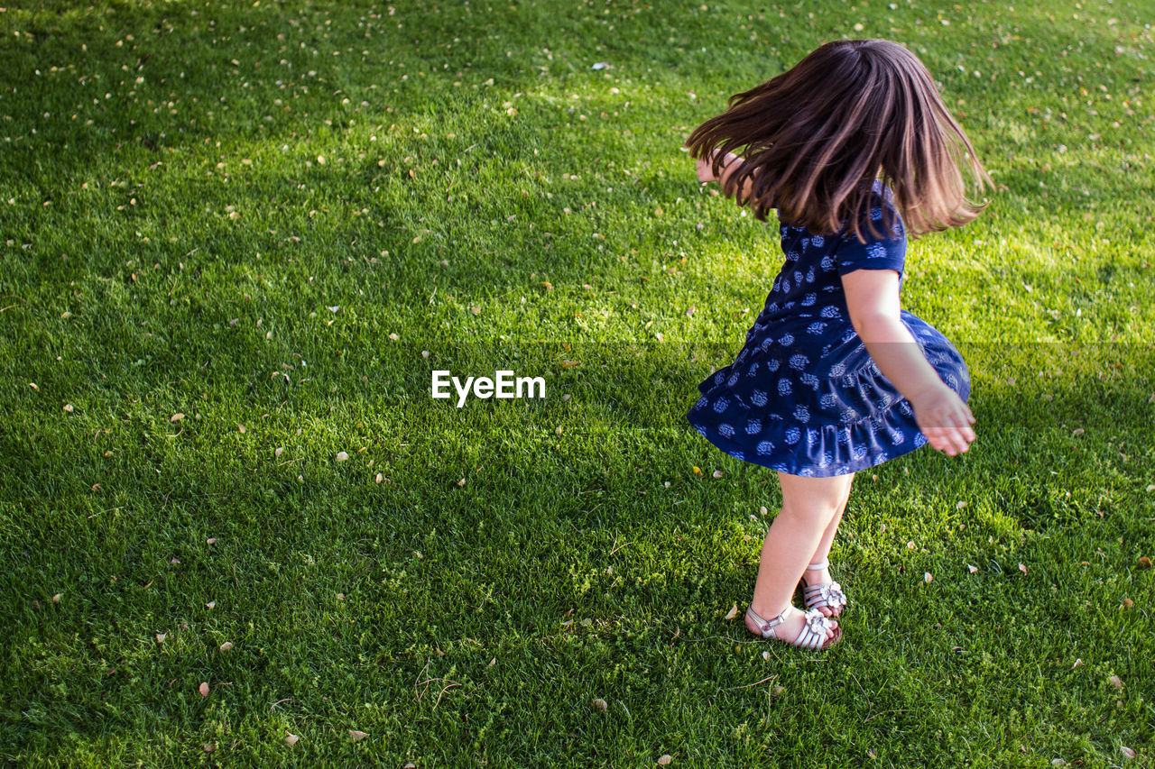 High angle view of girl tossing hair on lawn