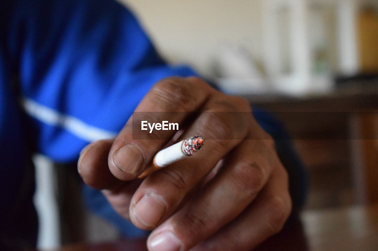 Close-up of man smoking cigarette at home