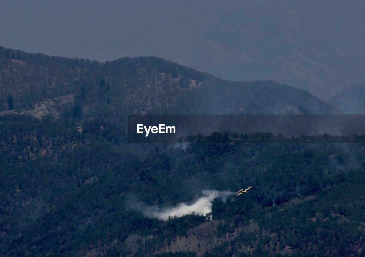 A canadian plane extinguish a fire in lago maggiore area and an aerial view of a hill