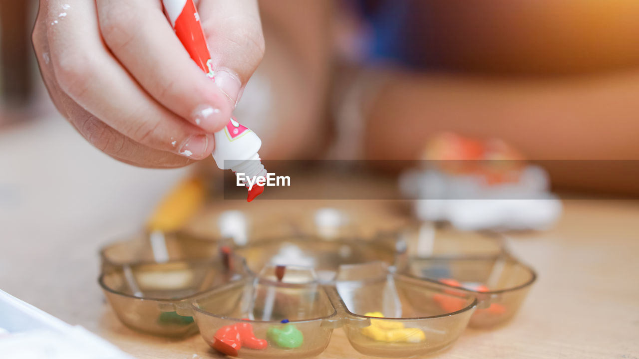 Close-up of person holding watercolor paints in home