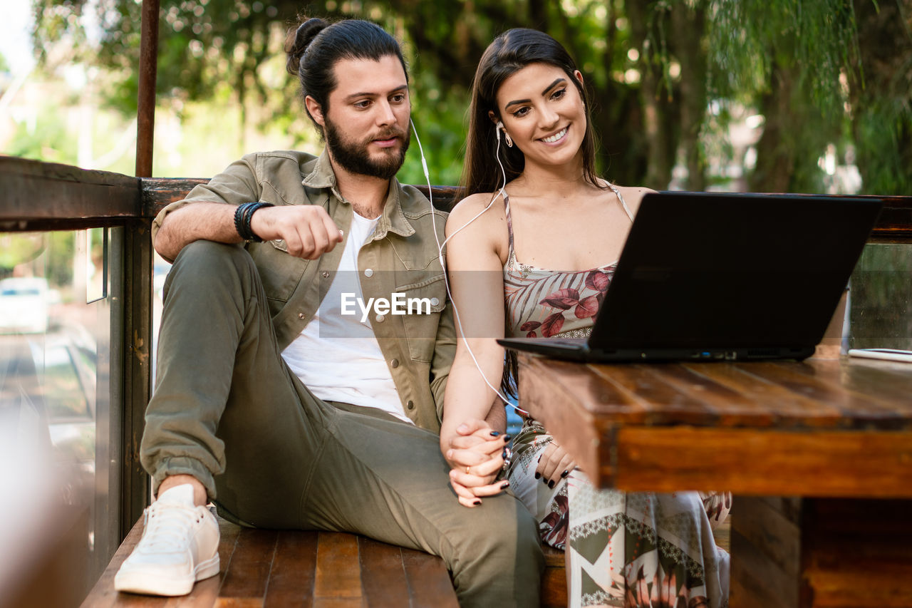 portrait of young woman using laptop while sitting on sofa at home