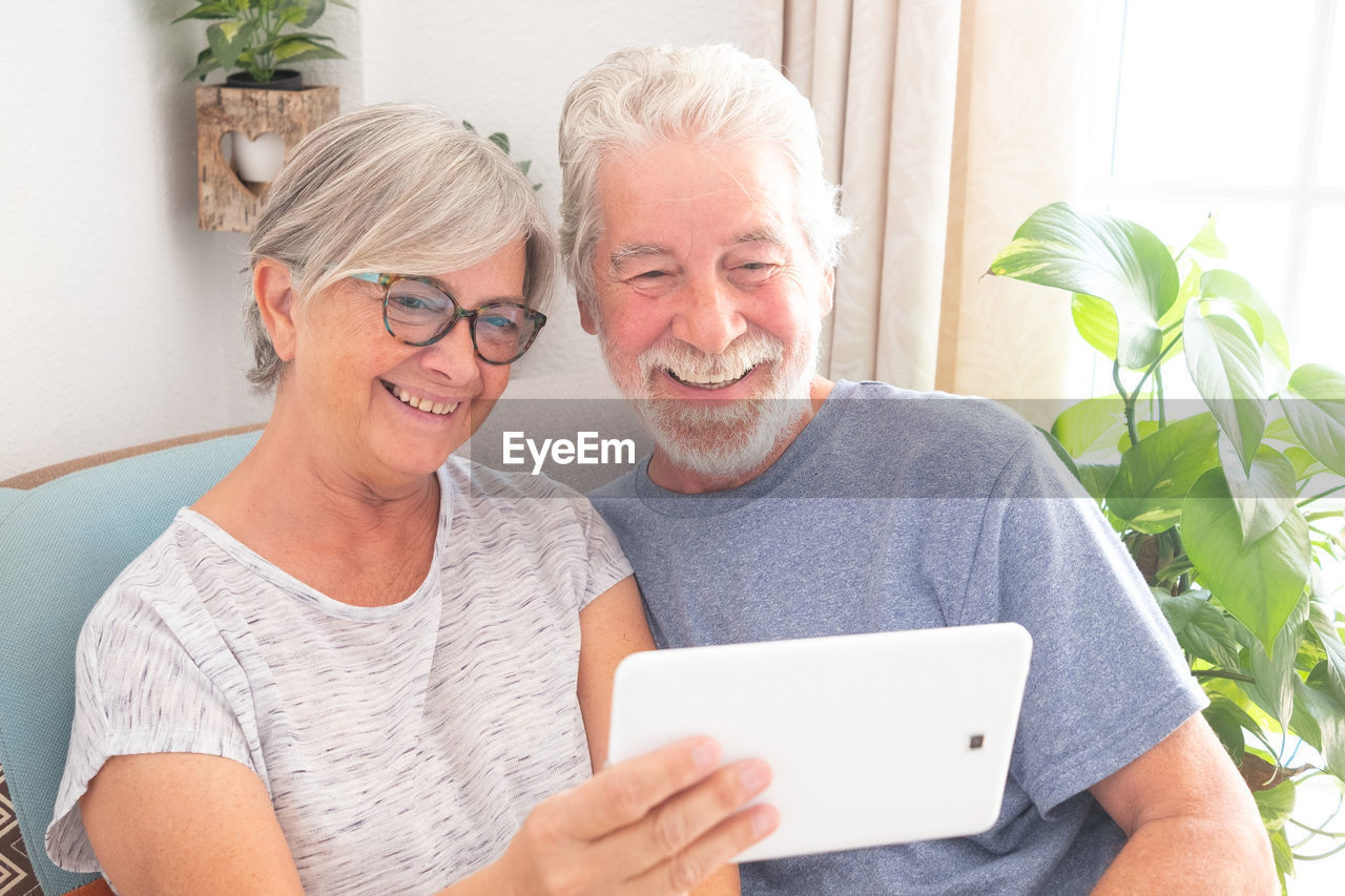Smiling couple using digital tablet at home