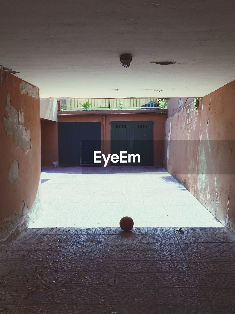 Soccer ball under tunnel shadow in courtyard