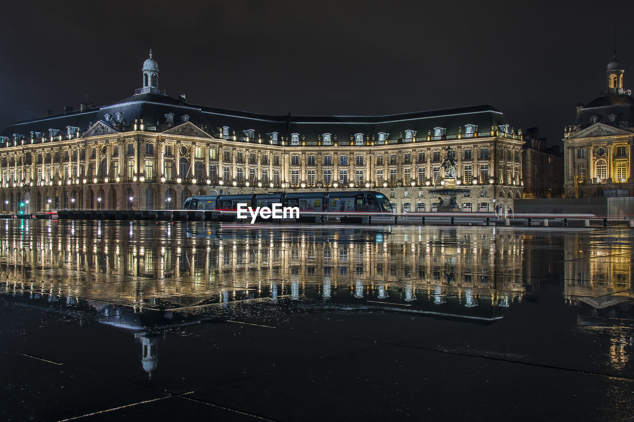 ILLUMINATED BUILDING BY LAKE AT NIGHT