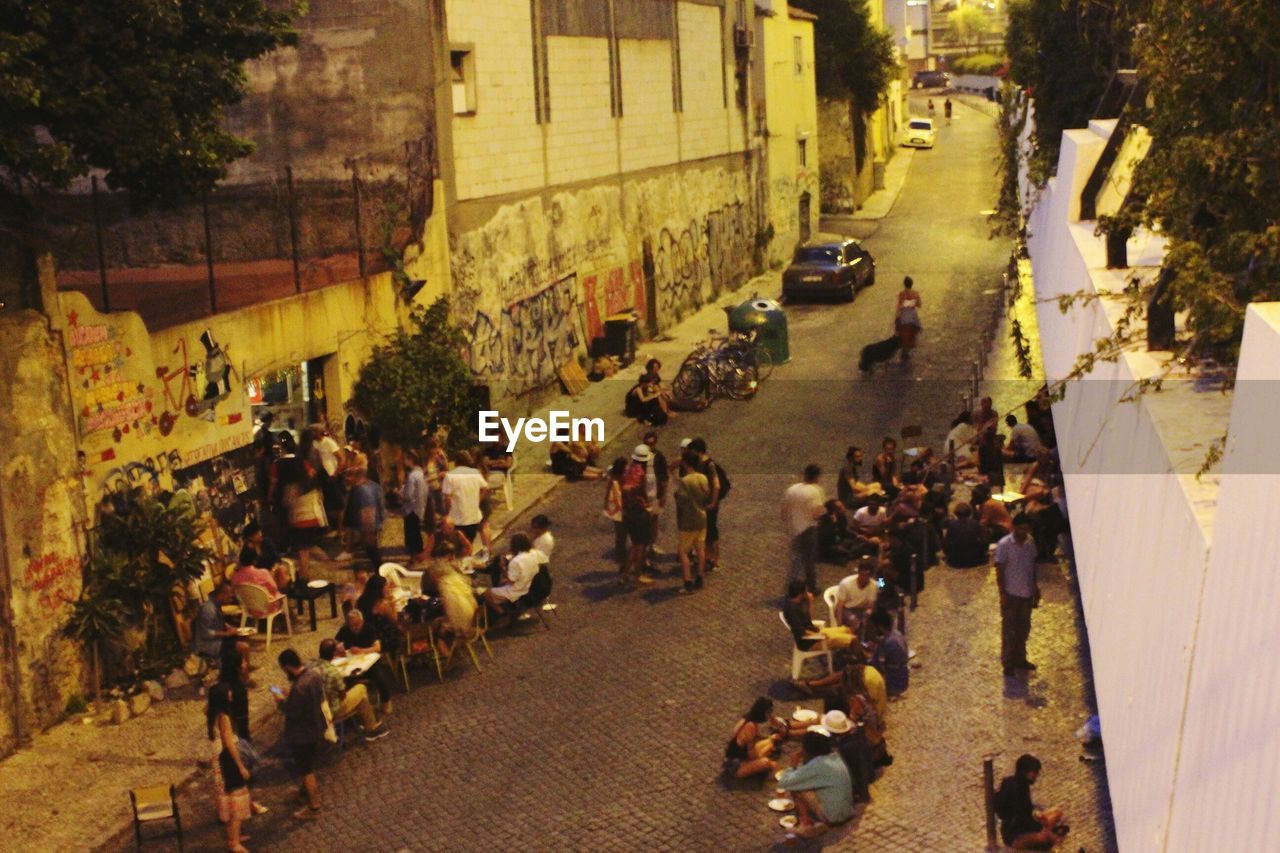 HIGH ANGLE VIEW OF CROWD ON STREET AMIDST BUILDINGS