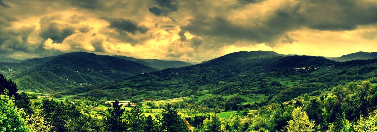 Panoramic shot of green mountains against cloudy sky