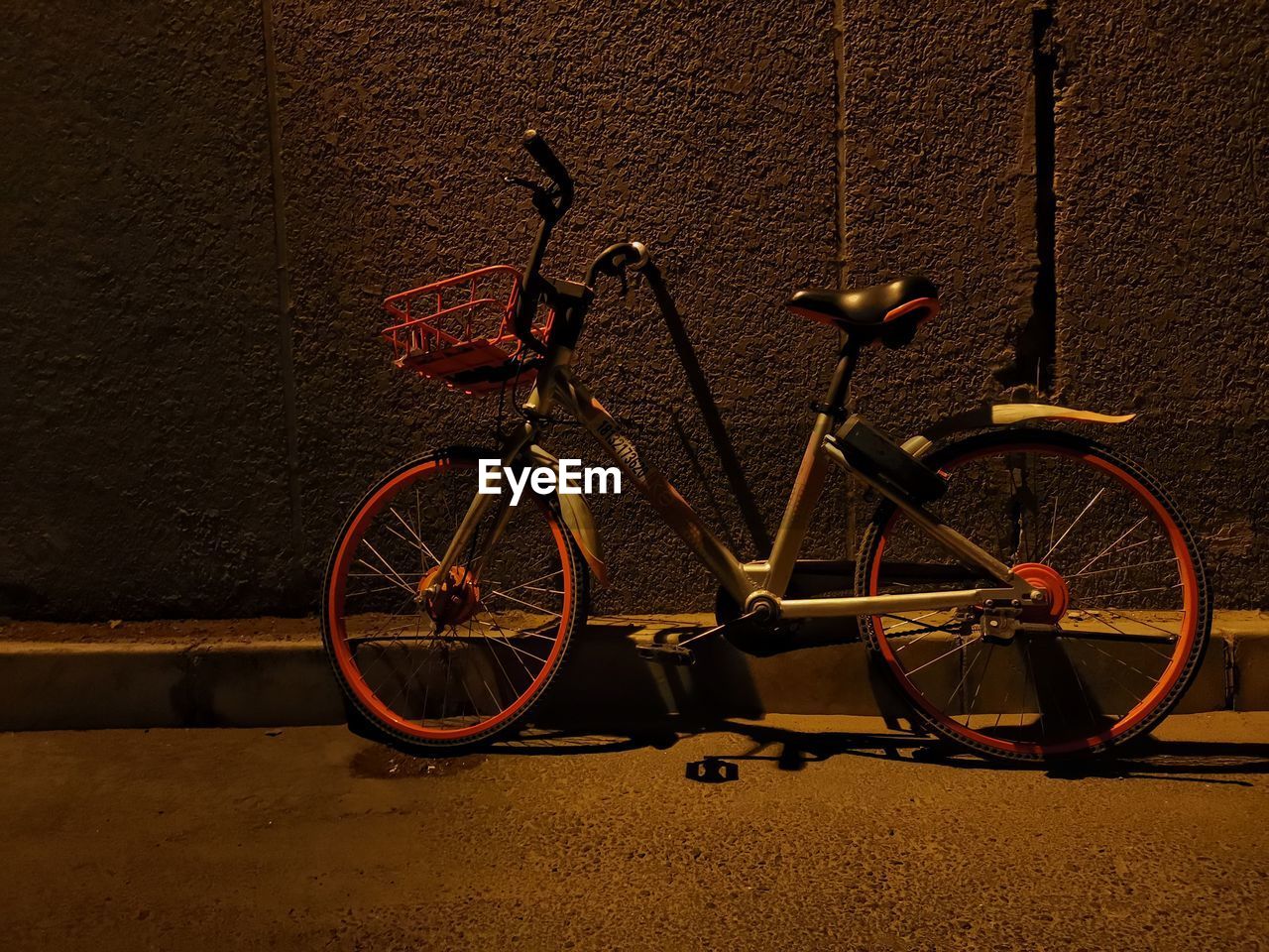 BICYCLE PARKED BY WALL