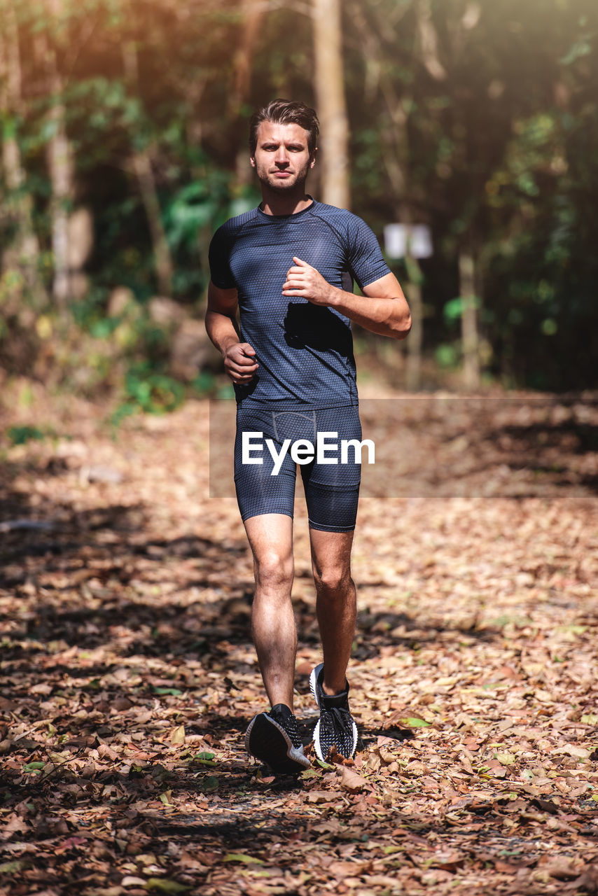 Full length portrait of man jogging in forest