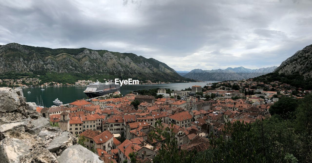 Aerial view of town by river and mountains against sky