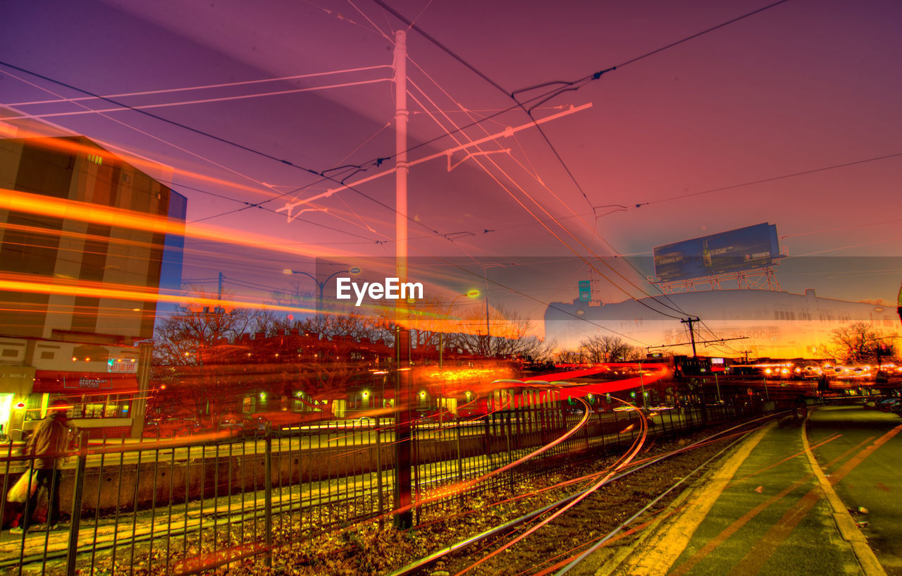 ILLUMINATED RAILROAD TRACKS AGAINST SKY AT SUNSET