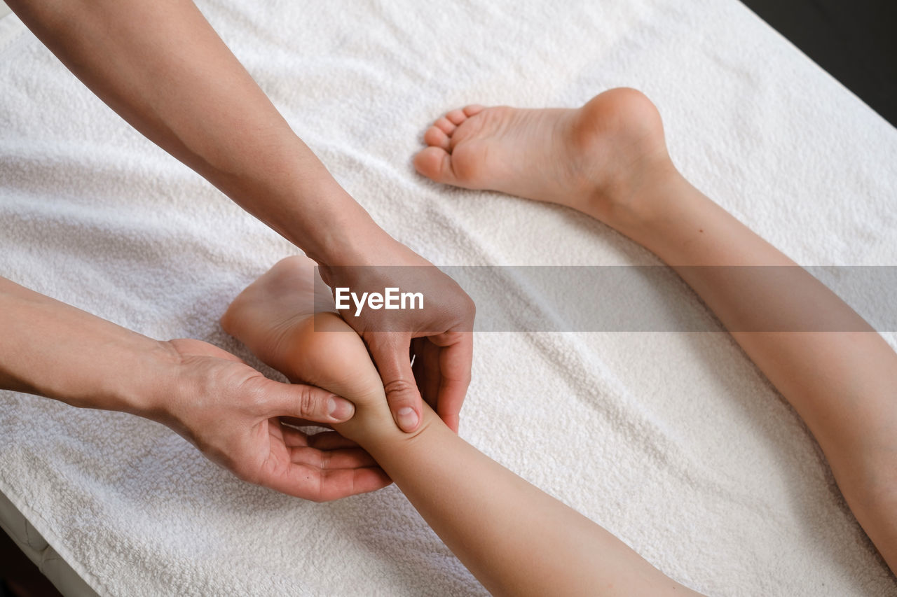Child foot massage treatment by professional massage therapist in spa resort. wellness, stress