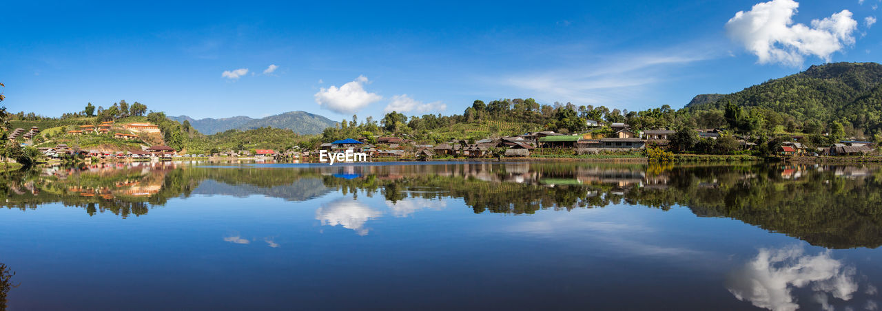 SCENIC VIEW OF LAKE BY BUILDINGS AND MOUNTAINS AGAINST SKY