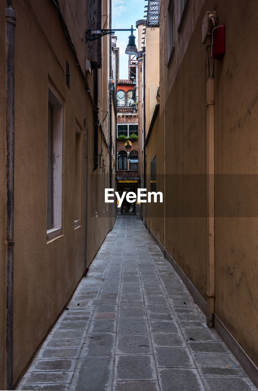 View in narrow lane in city of venice with entrance of a house at the end.