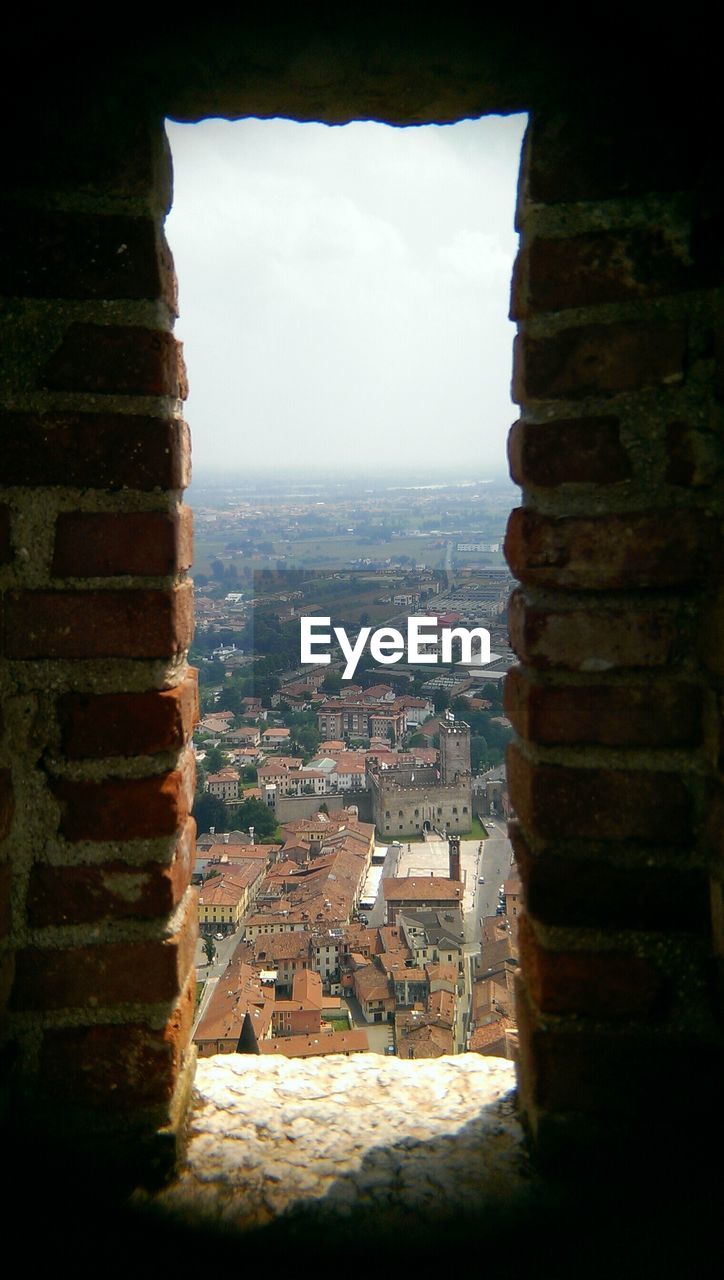 Urban rooftops as seen through a brick window frame