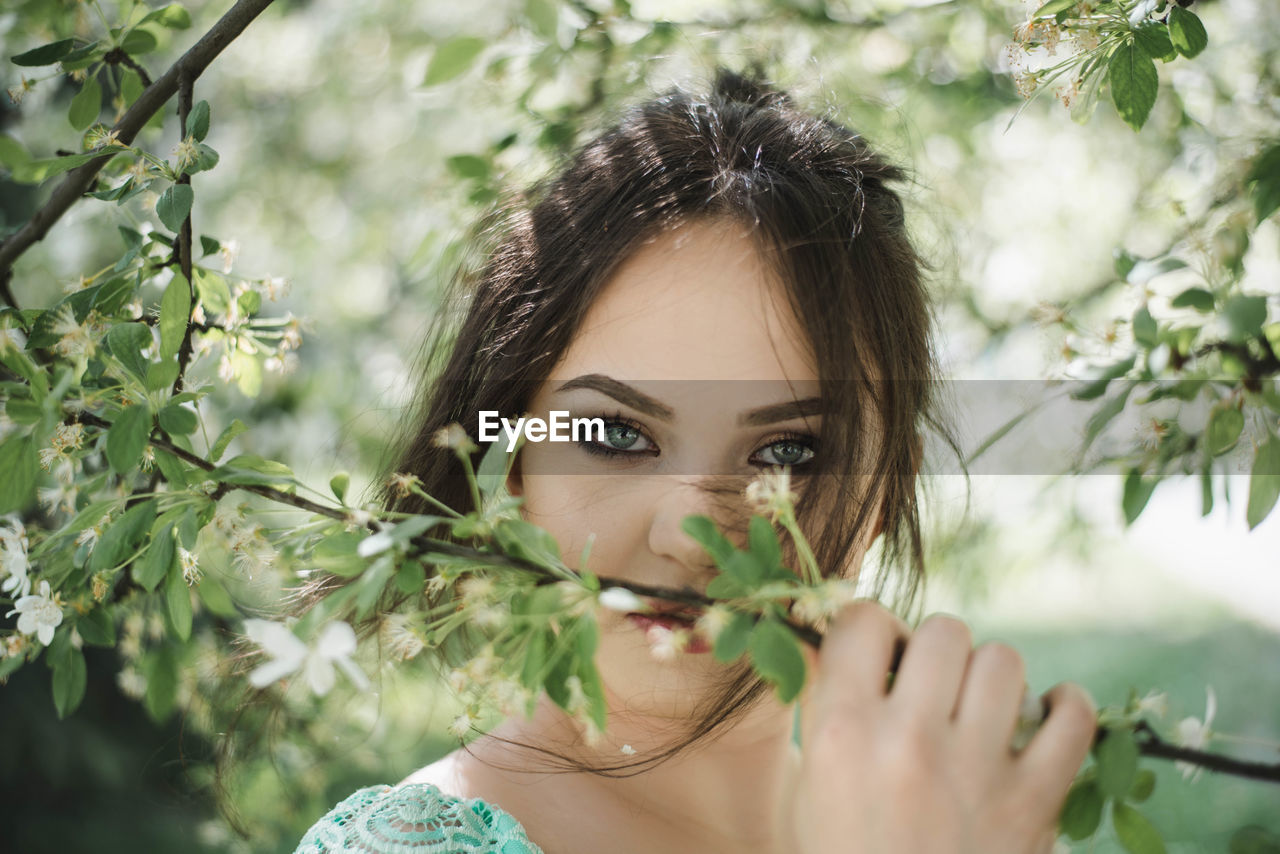 Portrait of beautiful young woman holding plants at park