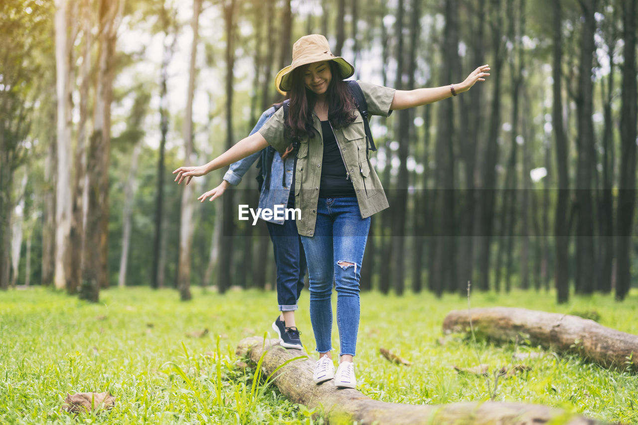 Friends walking on log in forest