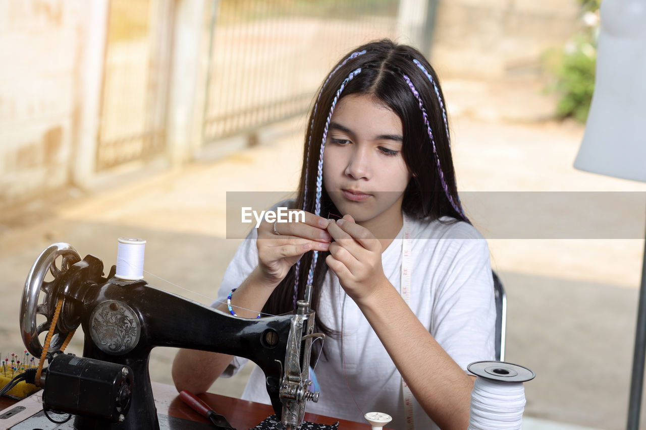 Girl putting thread in sewing needle