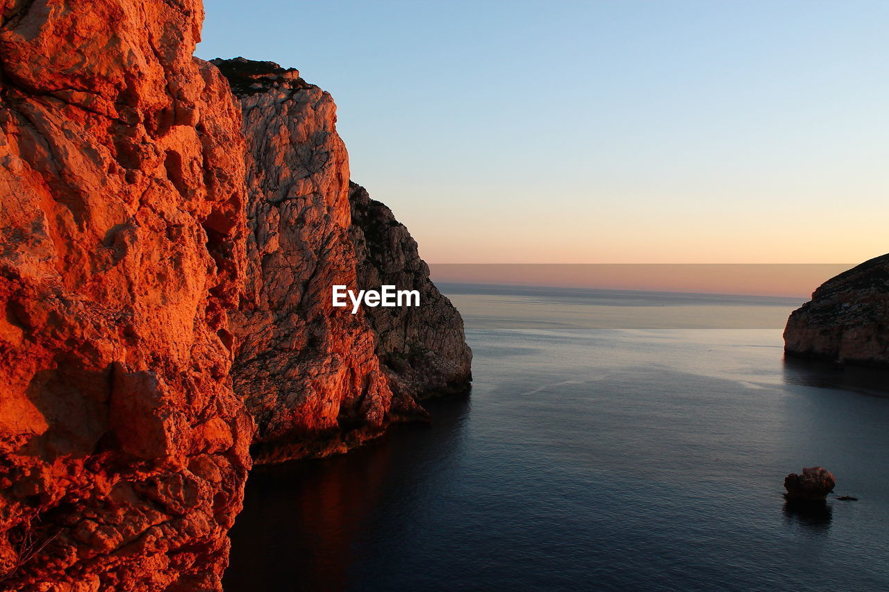 Rock formation in sea against clear sky