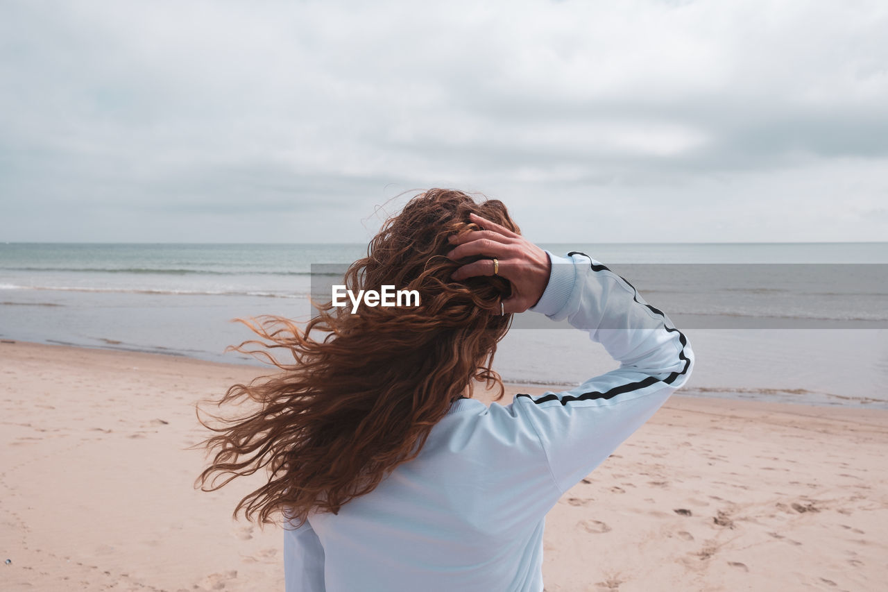 Woman standing at beach against sky