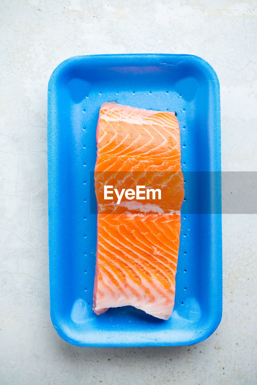 Fresh raw salmon in plastic container, close up view.