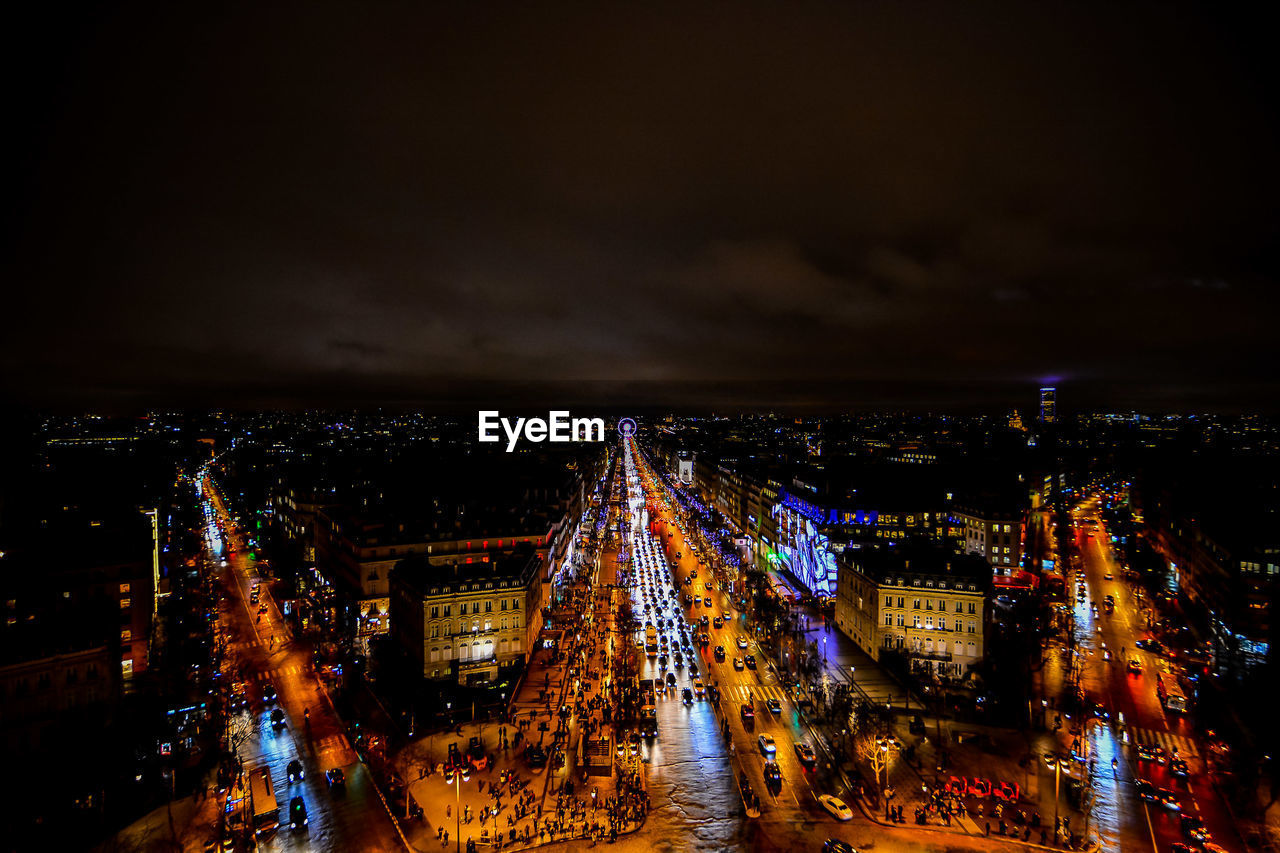 HIGH ANGLE VIEW OF ILLUMINATED STREET AMIDST BUILDINGS IN CITY