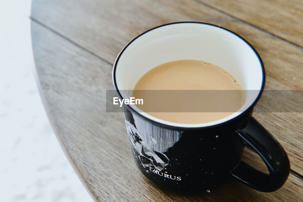 HIGH ANGLE VIEW OF COFFEE CUP ON WOODEN TABLE