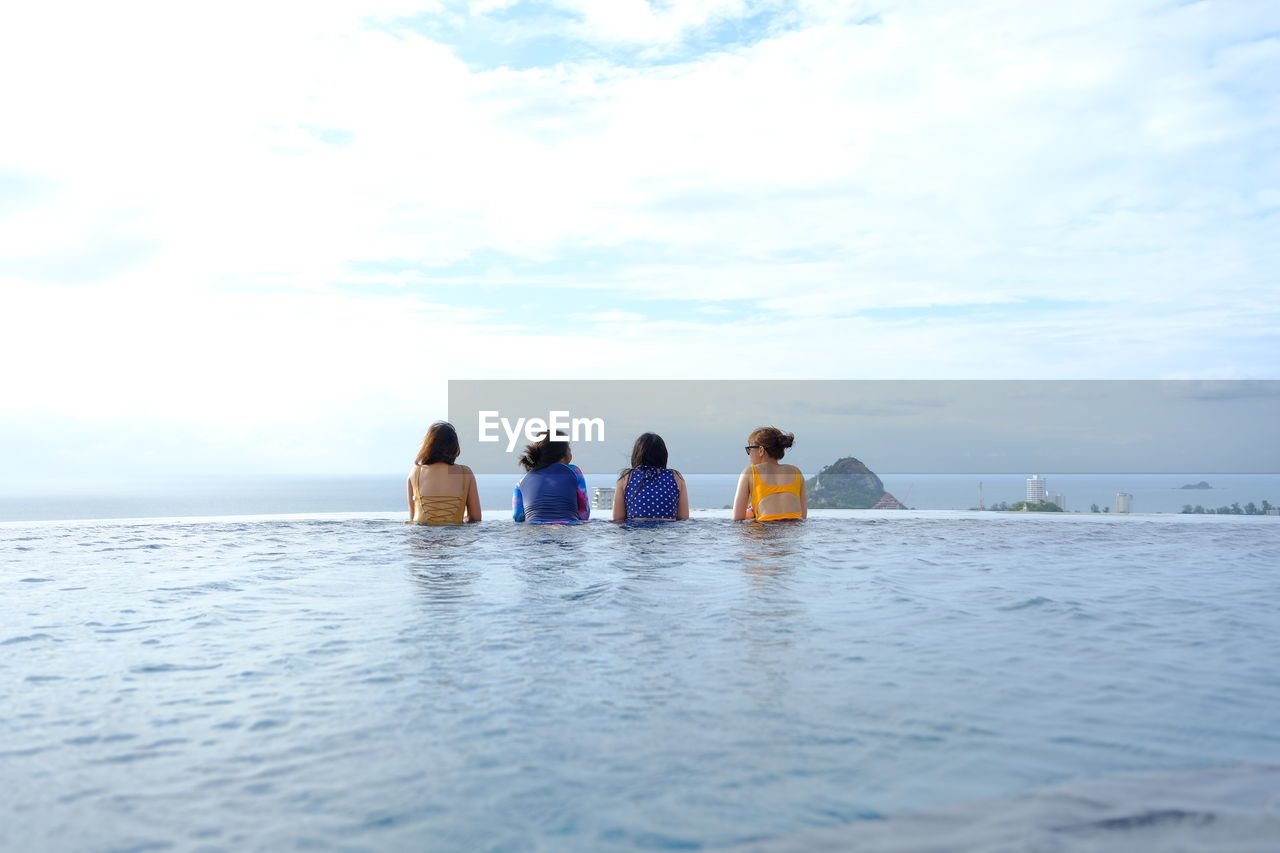 Rear view of friends relaxing in infinity pool