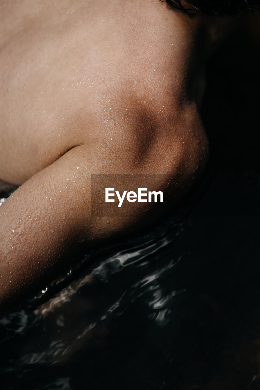 CLOSE-UP OF SHIRTLESS MAN WITH WATER