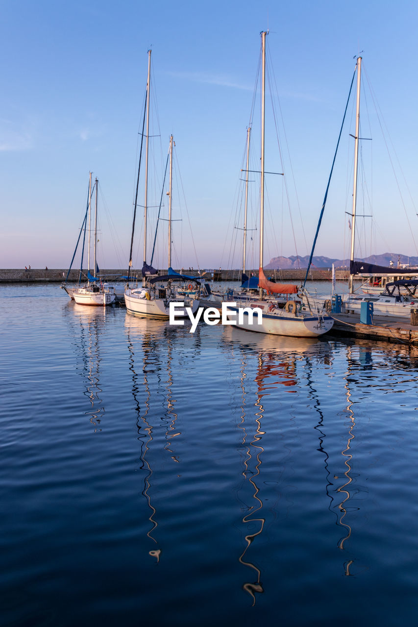 SAILBOATS MOORED AT HARBOR