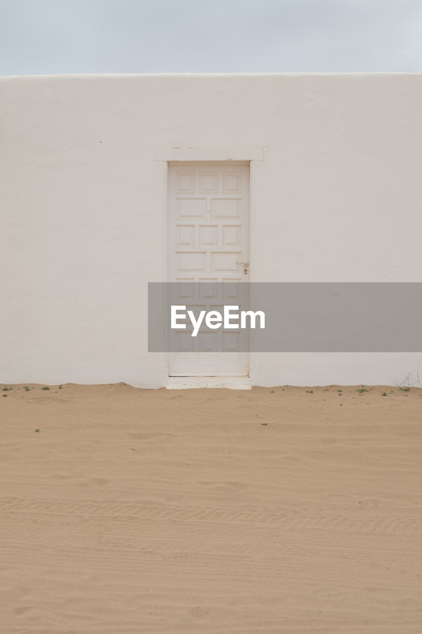 White door and wall  on sand desert landscape